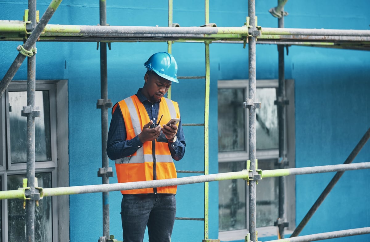 Worker coordinating with a phone and walkie-talkie on a construction site